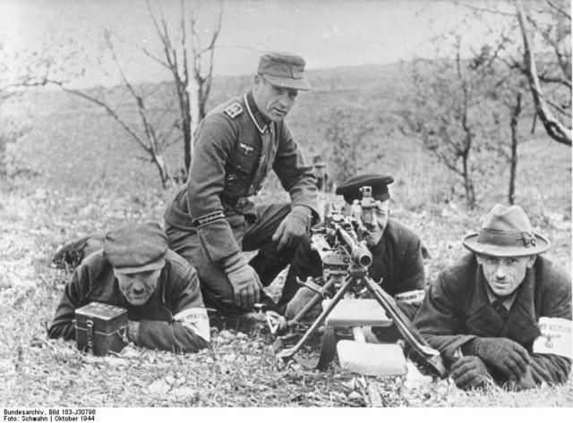Oberfeldwebel de la Grossdeutschland supervisa una stellung de schweren mg42, mg42 con trípode, administrada por hombres del Volkssturm. La caja de la izquierda contiene el visor acoplable. Octubre 1944, Prusia Oriental